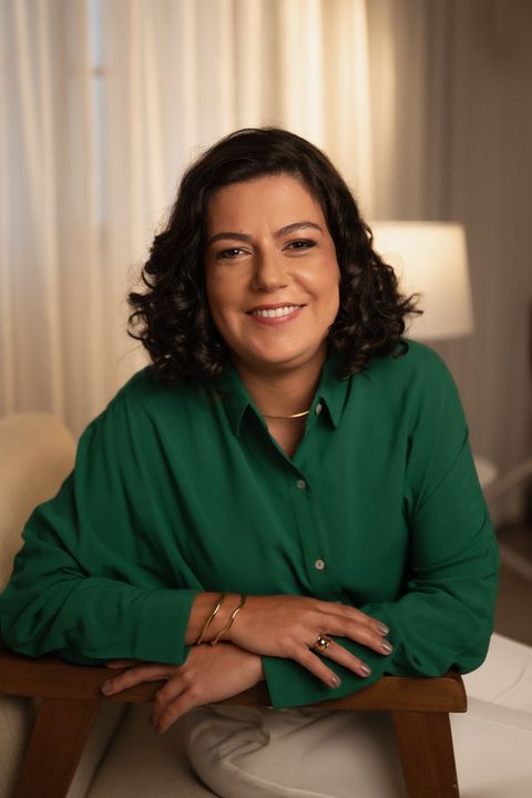 Retrato profissional da Dra. Thaís Ferreira Ortega, advogada especialista em direito empresarial e societário, sorrindo e vestindo traje social escuro em ambiente corporativo